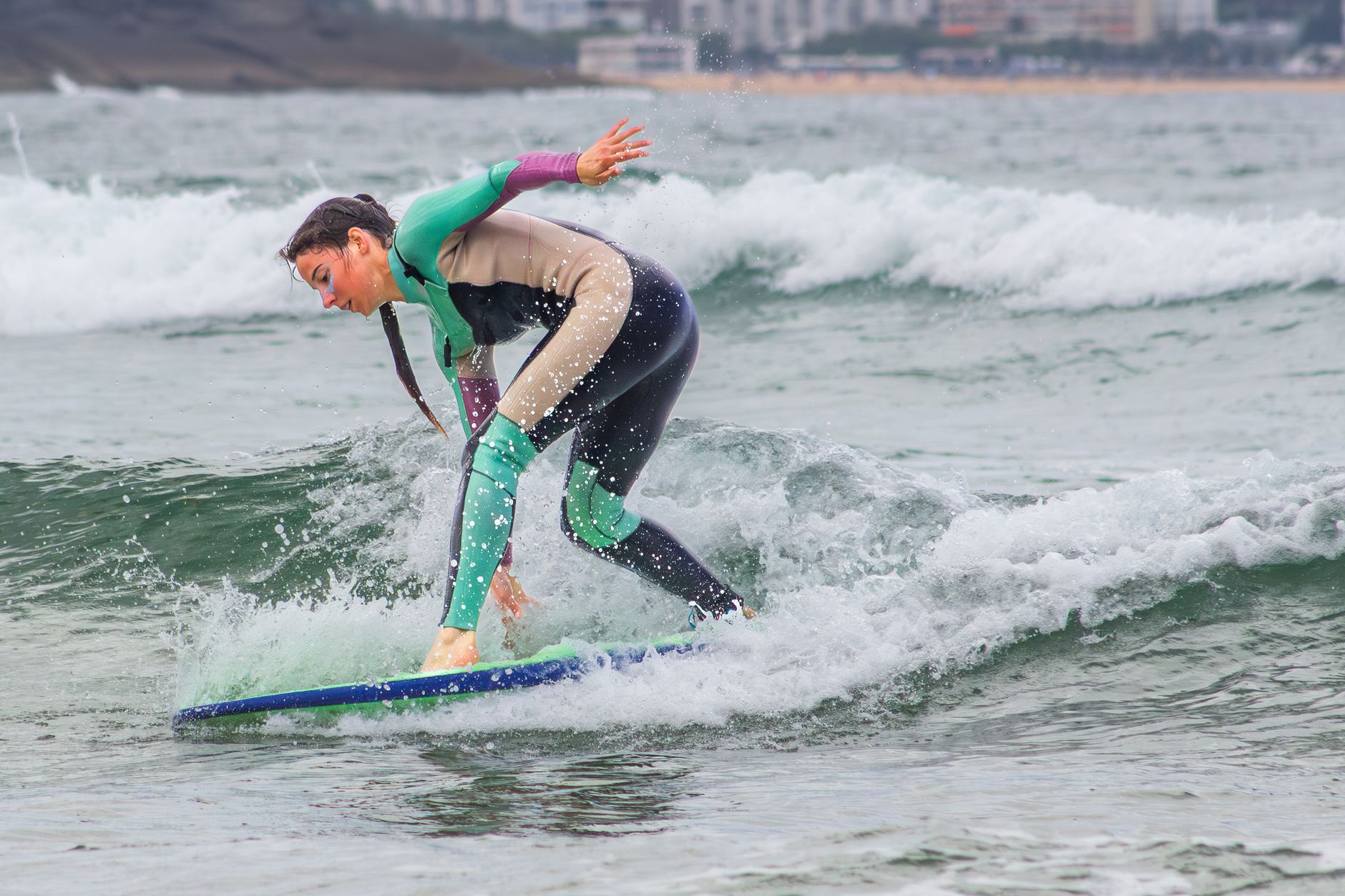 Rita Carvalho, head coach, smiling on the beach with a surfboard