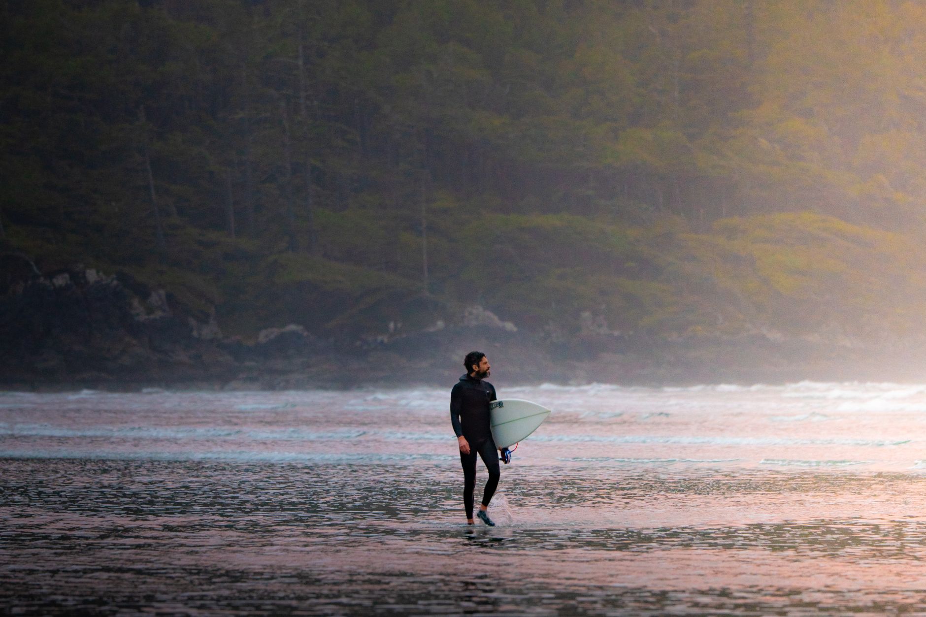 Tomás Figueira, performance coach, standing in a wetsuit at sunset